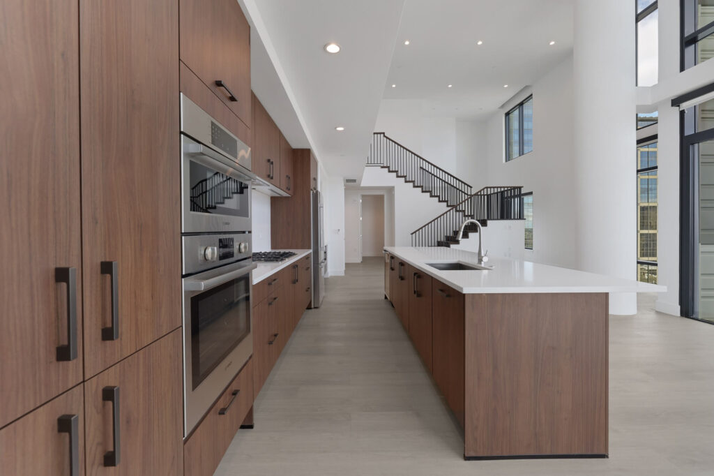 Interior of kitchen and dining room area with wood-style flooring, wood-style cabinets, stainless steel appliances, and stairs to second floor