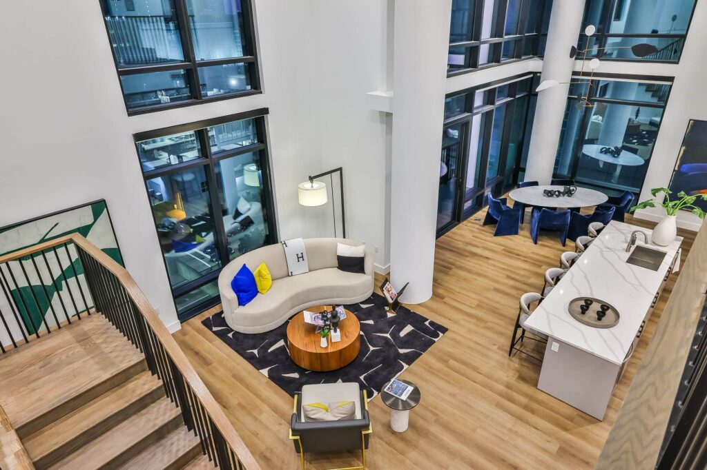 Second floor view of kitchen, dining room, and living room with dining table, couch, island seating, and wood-style flooring